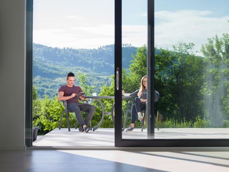 young beautiful handsome couple enjoying morning coffee and breakfast in front of their luxury home villa