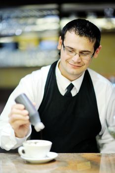 Barista prepares cappuccino in his coffee shop