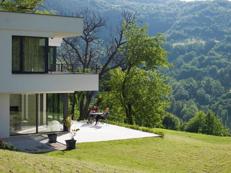 young beautiful handsome couple enjoying morning coffee and breakfast in front of their luxury home villa