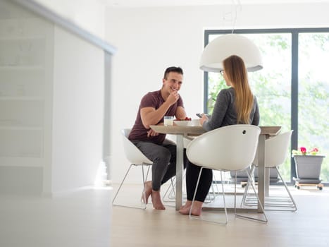 young beautiful handsome couple enjoying morning coffee and strawberries in their luxurious home villa