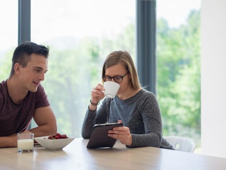 young beautiful handsome couple enjoying morning coffee and strawberries in their luxurious home villa