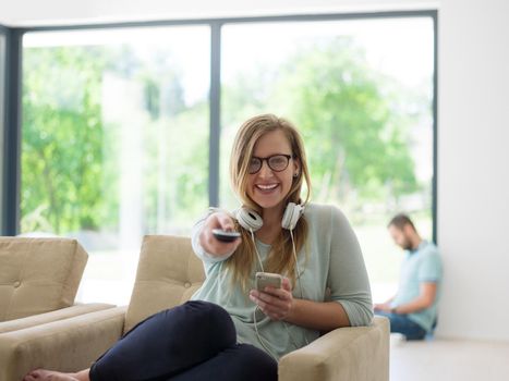 young handsome woman enjoying free time watching television in her luxury home villa