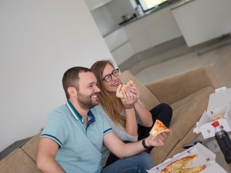 young handsome couple cheerfully spending time while eating pizza in their luxury home villa