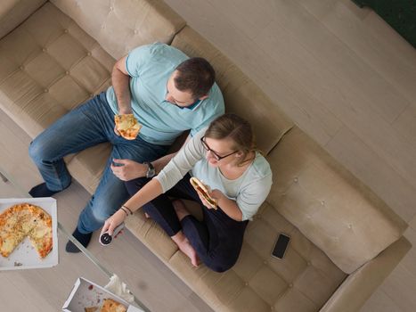 young handsome couple cheerfully spending time while eating pizza in their luxury home villa