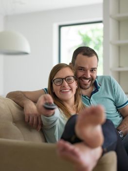 Young couple on the sofa watching television together in their luxury home