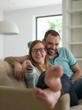 Young couple on the sofa watching television together in their luxury home