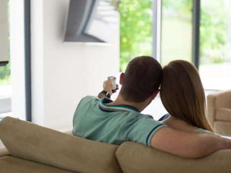 Young couple on the sofa watching television together in their luxury home