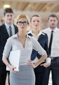 business woman standing with her staff in background at modern bright office conference room