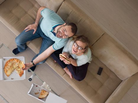 young handsome couple cheerfully spending time while eating pizza in their luxury home villa