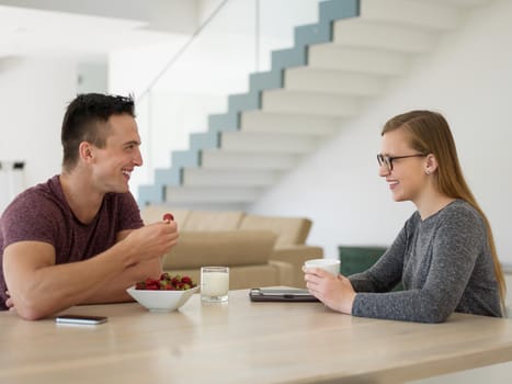 young beautiful handsome couple enjoying morning coffee and strawberries in their luxurious home villa