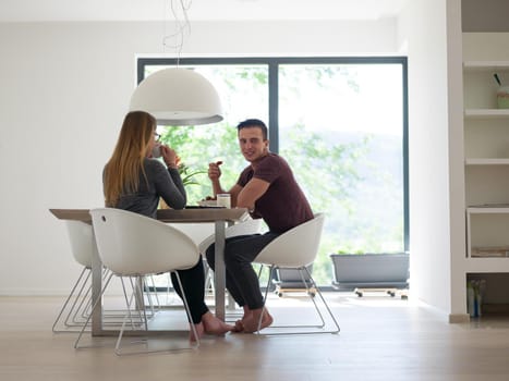 young beautiful handsome couple enjoying morning coffee and strawberries in their luxurious home villa