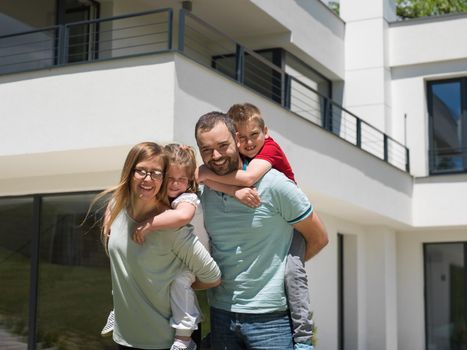 Portrait of young happy family with children in the yard in front of their luxury home of villa