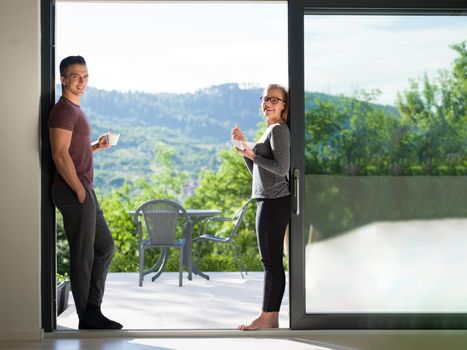 young beautiful handsome couple enjoying morning coffee and breakfast on the door of their luxury home villa