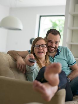 Young couple on the sofa watching television together in their luxury home