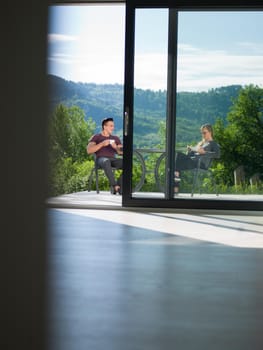 young beautiful handsome couple enjoying morning coffee and breakfast in front of their luxury home villa