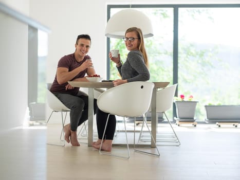 young beautiful handsome couple enjoying morning coffee and strawberries in their luxurious home villa