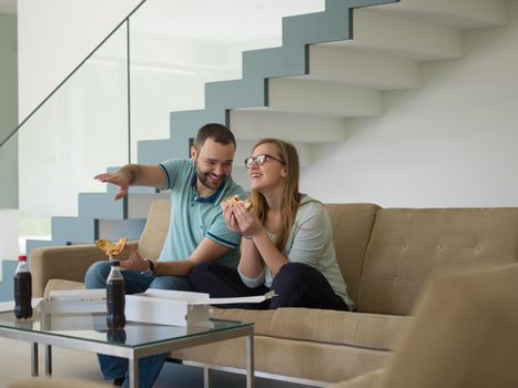 young handsome couple cheerfully spending time while eating pizza in their luxury home villa