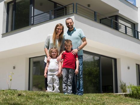 Portrait of young happy family with children in the yard in front of their luxury home of villa