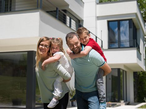 Portrait of young happy family with children in the yard in front of their luxury home of villa