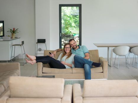 Young couple on the sofa watching television together in their luxury home