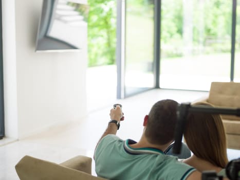 Young couple on the sofa watching television together in their luxury home