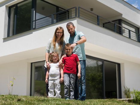 Portrait of young happy family with children in the yard in front of their luxury home of villa