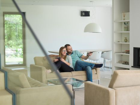 Young couple relaxes on the sofa in the luxury living room, using a tablet and remote control