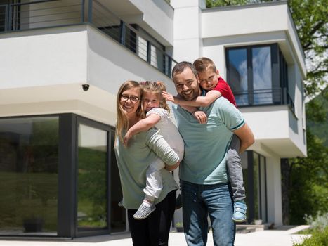 Portrait of young happy family with children in the yard in front of their luxury home of villa