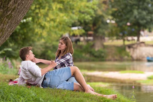 Couple in love enjoying picnic time drink and food in beautiful nature on the river bank