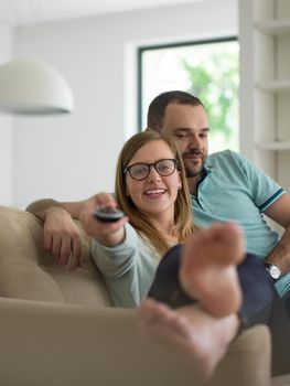 Young couple on the sofa watching television together in their luxury home