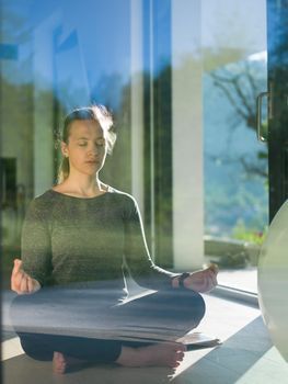 A young handsome woman doing yoga exercises on the floor of her luxury home villa