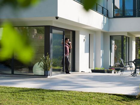 portrait of a young successful man drinking coffee in the doorway of his luxury home villa