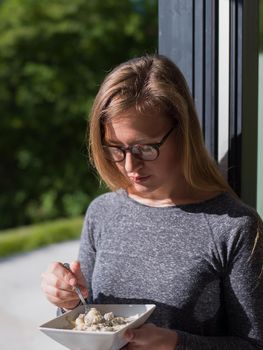 young beautiful successful woman eating breakfast in the doorway of her luxury home villa