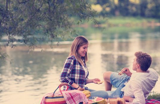 Couple in love enjoying picnic time drink and food in beautiful nature on the river bank