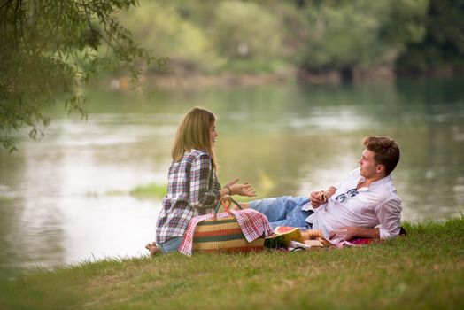 Couple in love enjoying picnic time drink and food in beautiful nature on the river bank