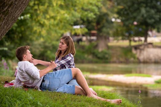 Couple in love enjoying picnic time drink and food in beautiful nature on the river bank