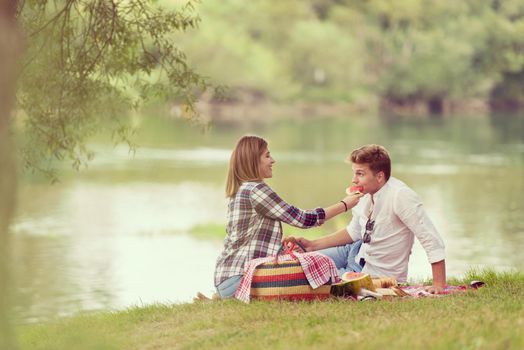 Couple in love enjoying picnic time drink and food in beautiful nature on the river bank