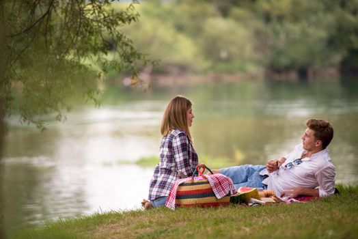 Couple in love enjoying picnic time drink and food in beautiful nature on the river bank