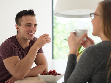 young beautiful handsome couple enjoying morning coffee and strawberries in their luxurious home villa