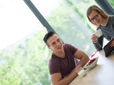 young beautiful handsome couple enjoying morning coffee and strawberries in their luxurious home villa