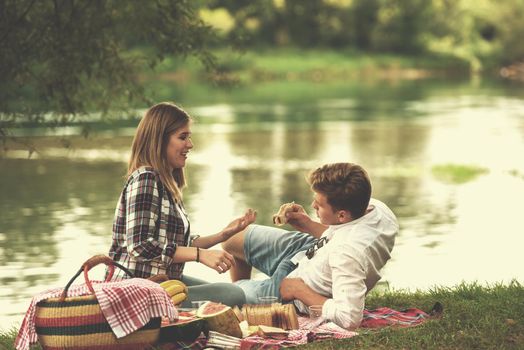 Couple in love enjoying picnic time drink and food in beautiful nature on the river bank