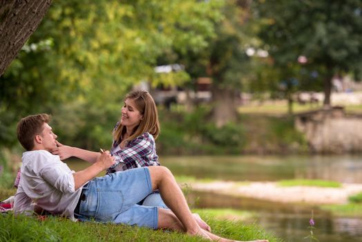 Couple in love enjoying picnic time drink and food in beautiful nature on the river bank