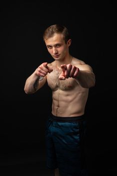 Man on black background keeps dumbbells pumped up in fitness active sexy arm muscular strong athletic dumbbell, person weightlifting. Attractive handsome metal, guy fit fingers point at us