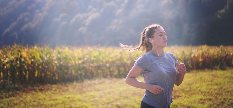 young woman enjoying in a healthy lifestyle while jogging along a country road, exercise and fitness concept