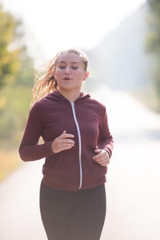 young woman enjoying in a healthy lifestyle while jogging along a country road, exercise and fitness concept