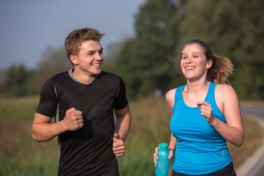 young couple enjoying in a healthy lifestyle while jogging along a country road, exercise and fitness concept