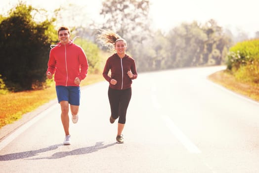 young couple enjoying in a healthy lifestyle while jogging along a country road, exercise and fitness concept