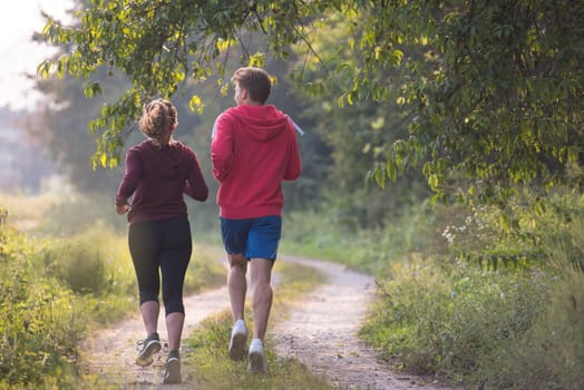 young couple enjoying in a healthy lifestyle while jogging along a country road, exercise and fitness concept