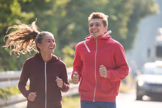 young couple enjoying in a healthy lifestyle while jogging along a country road, exercise and fitness concept