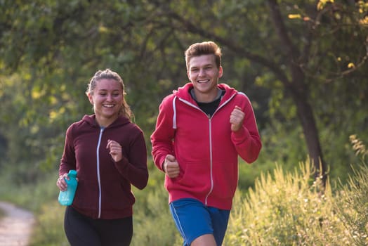 young couple enjoying in a healthy lifestyle while jogging along a country road, exercise and fitness concept